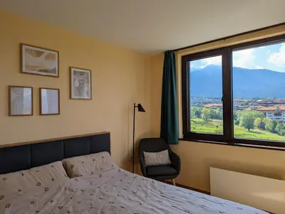 a bedroom with a bed and a chair and a window at Stylish 2BD Apartment with Panoramic Mountain View by Flat Mаnager in Bansko