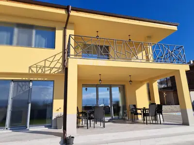 a yellow house with a balcony with a table and chairs at Sunset view guest house in Ilindentsi