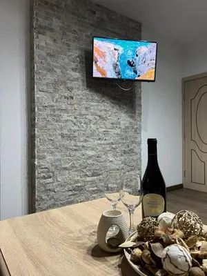 a table with two wine glasses and a tv on a brick wall at Guest House Tanevi in Devin