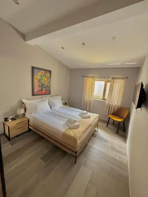 a bedroom with a large bed and a chair at Вила Рафаела-Мартина in Dobrinishte