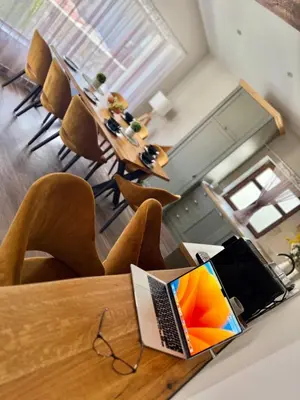 a laptop computer sitting on a wooden table with chairs at Вила Рафаела-Мартина in Dobrinishte