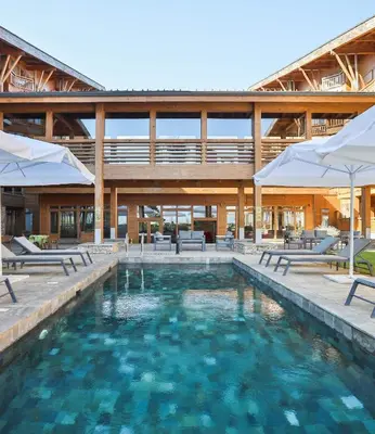 a pool with chairs and umbrellas in front of a building at Pirin Golf SPA Studio Mountain View Compass Property in Bansko