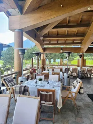 a restaurant with white tables and chairs on a patio at Pirin Golf SPA Studio Mountain View Compass Property in Bansko