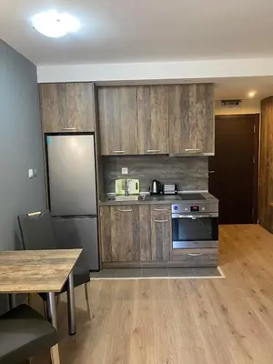 a kitchen with wooden cabinets and a table and a refrigerator at Grand Apartments in Bansko
