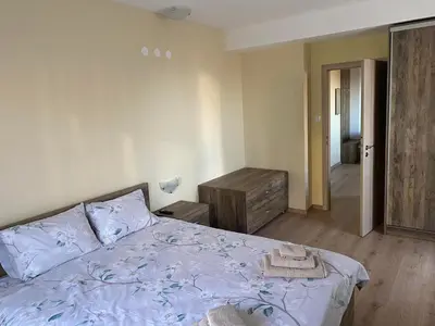 a bedroom with a bed with blue sheets and a dresser at Grand Apartments in Bansko