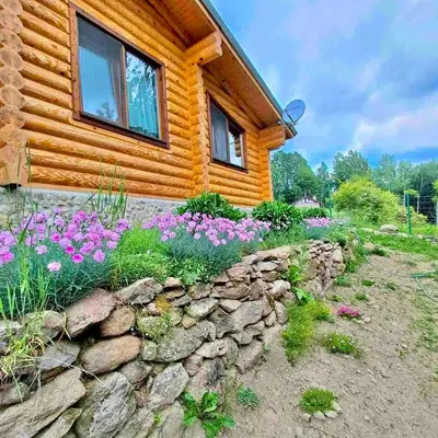 a log cabin with flowers in front of it at Вила Брезите in Pamporovo