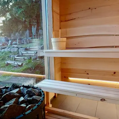 a wooden sauna with a window and a basket of rocks at Вила Брезите in Pamporovo