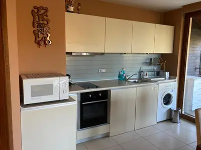 a kitchen with white cabinets and a sink and a microwave at Апартамент за гости Свети Трифон in Pamporovo