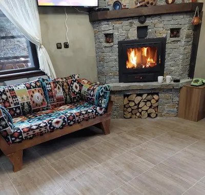 a living room with a couch and a fireplace at Къщи за гости НЕСИ in Leshten