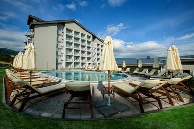 a pool with chairs and umbrellas in front of a hotel at Парк хотел Кюстендил in Kyustendil