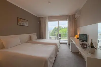 a hotel room with two beds and a window at Парк хотел Кюстендил in Kyustendil