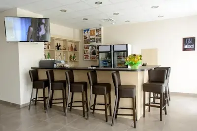 a bar with chairs and a counter with a television at Парк хотел Кюстендил in Kyustendil
