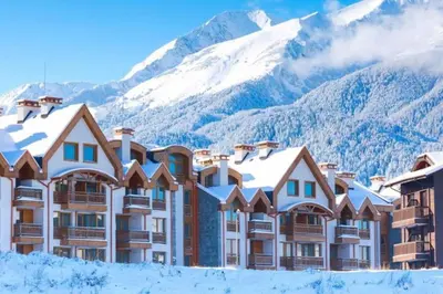 a hotel with snow covered mountains in the background at Warm&Cozy Studio with Patio in Bansko