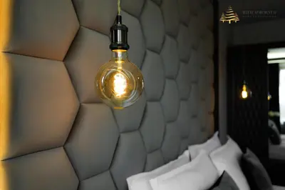 a lamp hanging over a bed with white pillows at Deluxe Apartment 33 Mountain Lodge Pamporovo in Pamporovo