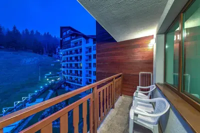 a balcony with two chairs and a view of a building at Форест Нук - апартамент in Pamporovo