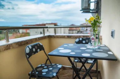 a table with chairs and a vase of flowers on a balcony at Apartament Tiana Lux in Hisarya