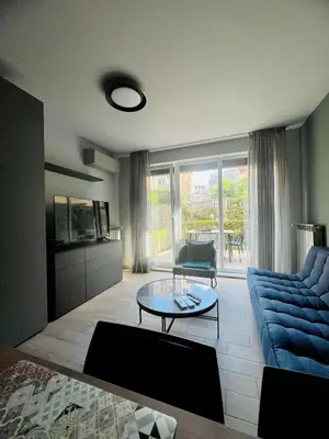 a living room with a blue couch and a glass table at 7th Sense boutique apartments in Sofia