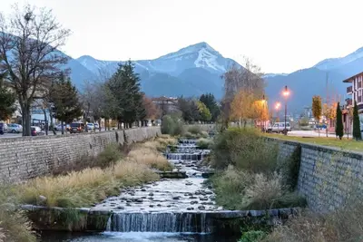 a creek in a city with mountains in the background at Cosy room in the center of Bansko in Bansko