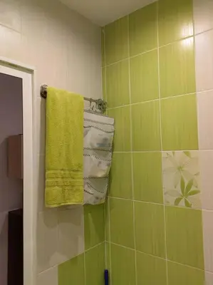 a bathroom with green tiled walls and towels at Alexander Apartments Kyustendil in Kyustendil