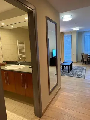 a bathroom with a mirror and a sink and a living room at Lodge Euphoria Apartment in Borovets