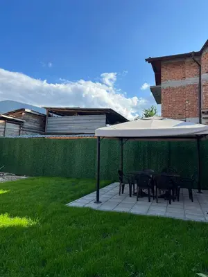 a table and chairs under an umbrella on a patio at Стаи за гости Валеьови in Bansko