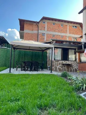 a patio with a table and a large umbrella at Стаи за гости Валеьови in Bansko