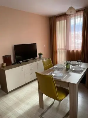 a dining room with a table with chairs and a television at Mila's 1 Bedroom Apartment in Sofia