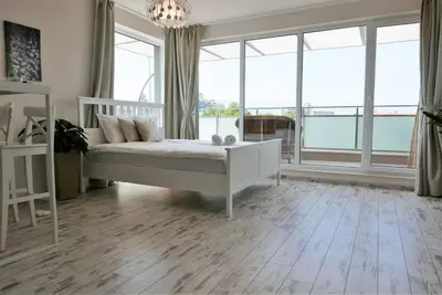 a bedroom with a white bed and large windows at Charmful new flat with Hill view in Plovdiv