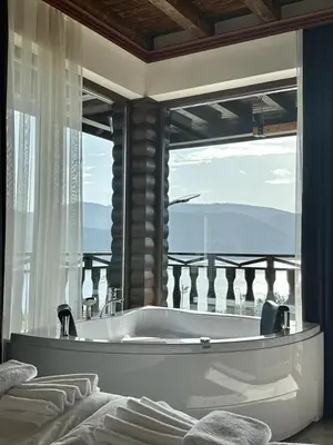 a bath tub in a room with a large window at Villa ART in Dospat
