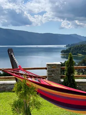 a hammock on a fence with a view of a lake at Villa ART in Dospat