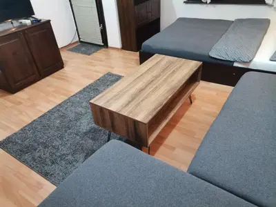 a room with two beds and a wooden coffee table at Quiet central studio in Pazardzhik
