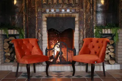 two orange chairs in front of a fireplace at Armaco Residence in Koprivshtitsa
