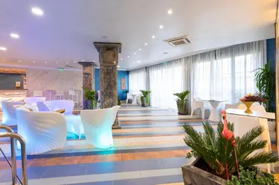 a lobby with white chairs and tables and windows at Armaco Residence in Koprivshtitsa