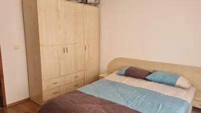a bedroom with a bed and a wooden cabinet at Банско Апартментс in Bansko