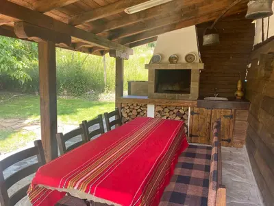 an outdoor kitchen with a red blanket on a table at Къща за гости НОВЕ in Terziysko