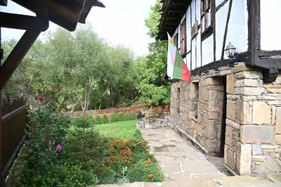 a flag on the side of a stone building with a garden at Къща за гости НОВЕ in Terziysko