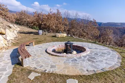 a stone patio with a fire pit and a bench at Комплекс Конна база Асгард in Golem Tsalim