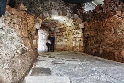 a person walking through a tunnel in a stone building at Студио Римски Стадион in Plovdiv