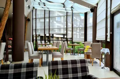 a restaurant with tables and chairs and windows at Aspen Golf Resort and SPA in Bansko