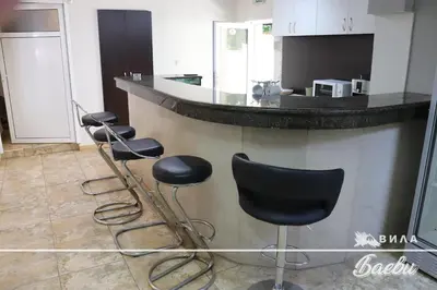 a kitchen with a bar with stools in front of it at ВИЛА БАЕВИ in Velingrad