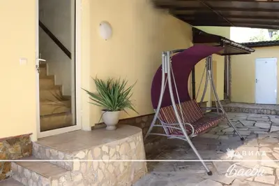 a porch of a house with a chair at ВИЛА БАЕВИ in Velingrad
