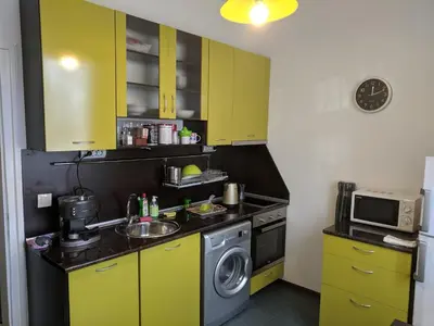 a kitchen with yellow cabinets and a washing machine at Convenient New Apartment Near Metro Station by Flat Mаnager in Sofia