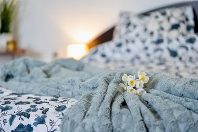 a blue and white bed with a flower on it at Cozy 1-Bedroom flat in the very Center of Sofia in Sofia