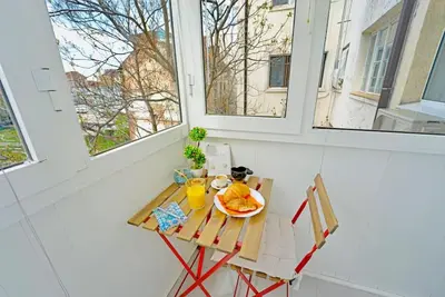 a table with a plate of food on it in a room with windows at Cozy 1-Bedroom flat in the very Center of Sofia in Sofia