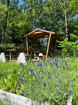 a wooden picnic shelter in a garden with purple flowers at Time Traveling Apartment Sofia Mladost District in Sofia