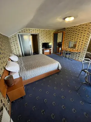 a hotel room with a large bed and a desk at Хотел ПАНОРАМА ДОСПАТ in Dospat