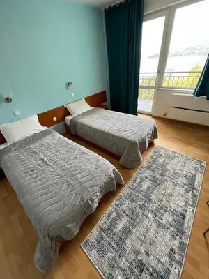 two beds in a room with two rugs on the floor at Хотел ПАНОРАМА ДОСПАТ in Dospat