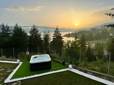 a hot tub on a lawn with the sunset in the background at Villa Siesta Dospat in Dospat