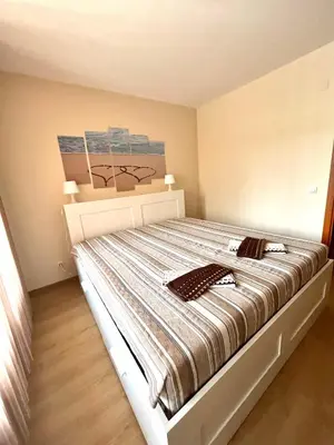 a bedroom with a bed with a striped comforter at Апартамент Ренета Apartment Reneta in Velingrad