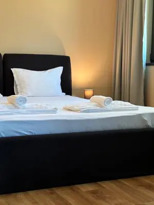 a bed with white sheets and towels on it at SPA Apartments Perun in Sandanski